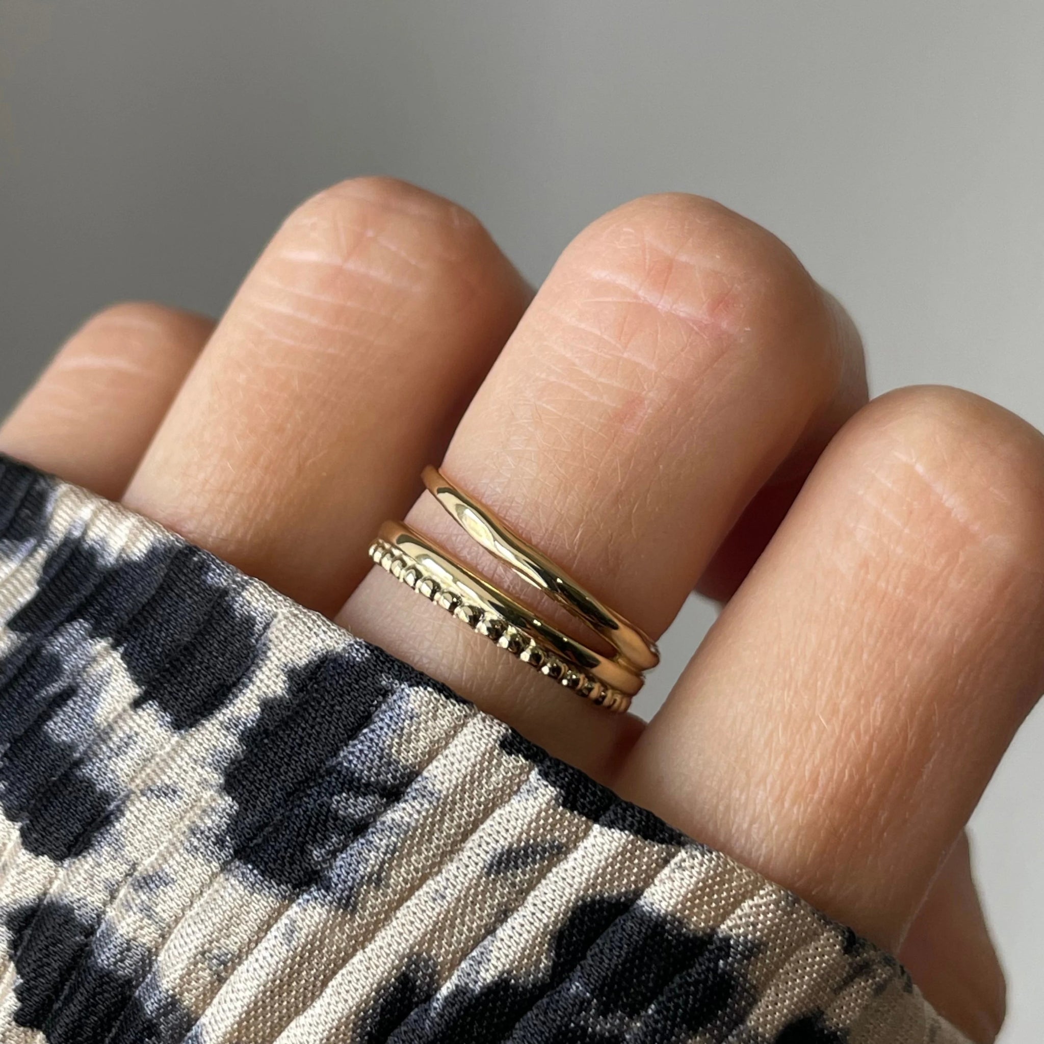 Gros plan bague Ursula effet superposition deux anneaux (lisse et perlé) portée au doigt, style minimaliste.