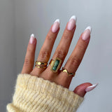 Bague Veronika portée en accumulation (stacking) avec la bague vague Andrea et d'autres anneaux dorés.