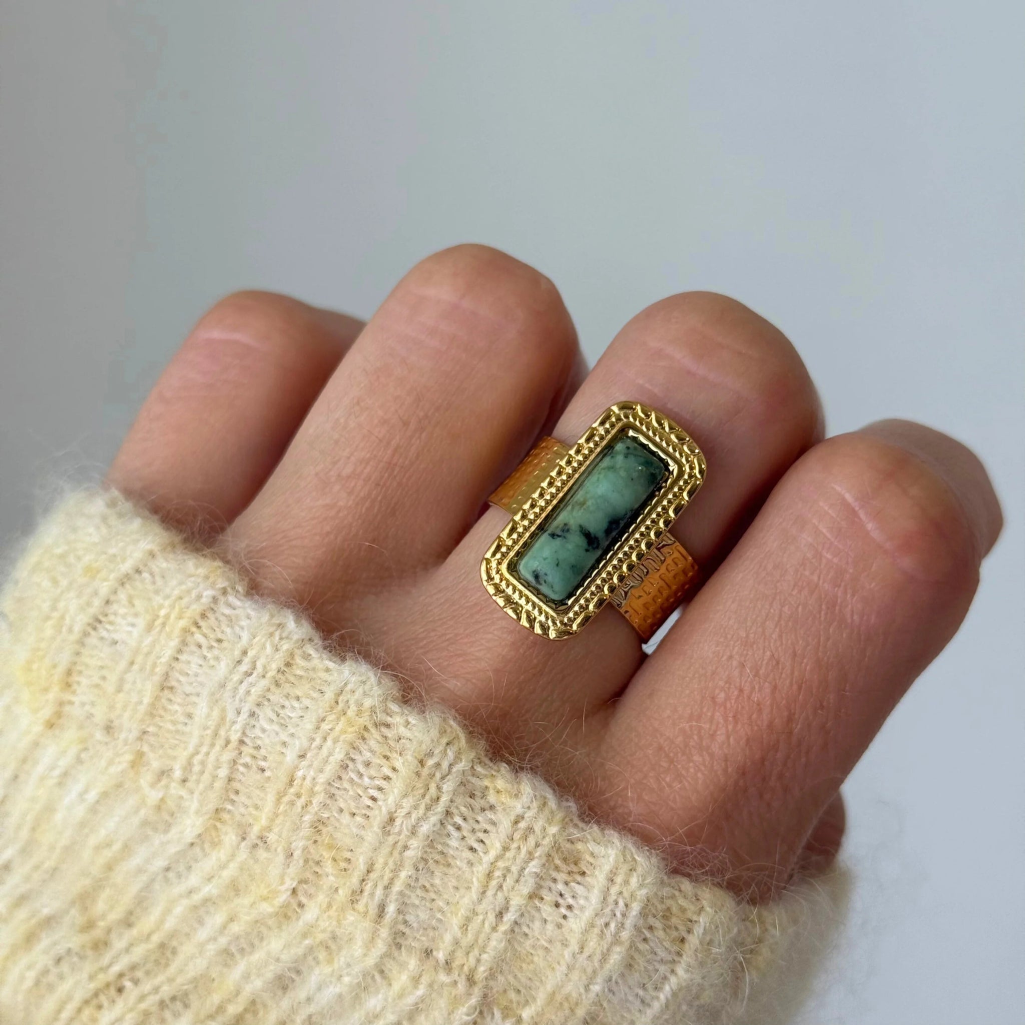 Gros plan bague Veronika style vintage avec pierre rectangulaire verte portée au doigt, accessoire bohème chic.