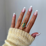 Gros plan bague Veronika style vintage avec pierre rectangulaire verte portée au doigt, accessoire bohème chic.