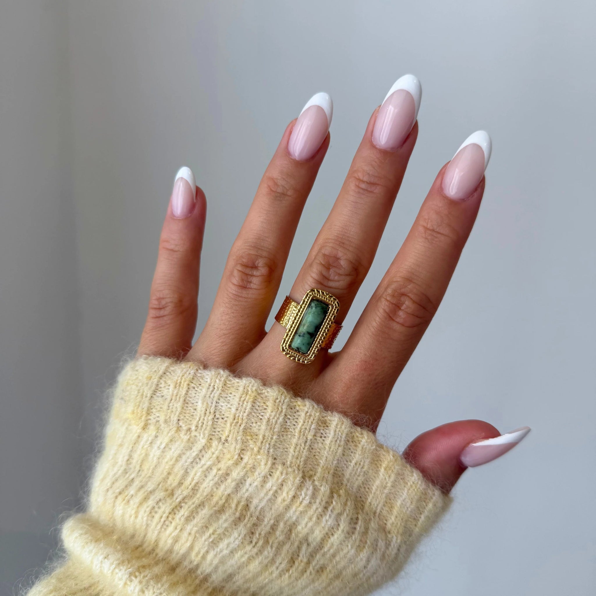 Gros plan bague Veronika style vintage avec pierre rectangulaire verte portée au doigt, accessoire bohème chic.