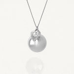 Bola de grossesse argenté porté sur le ventre rond d'une femme enceinte, bijou de maternité apaisant.