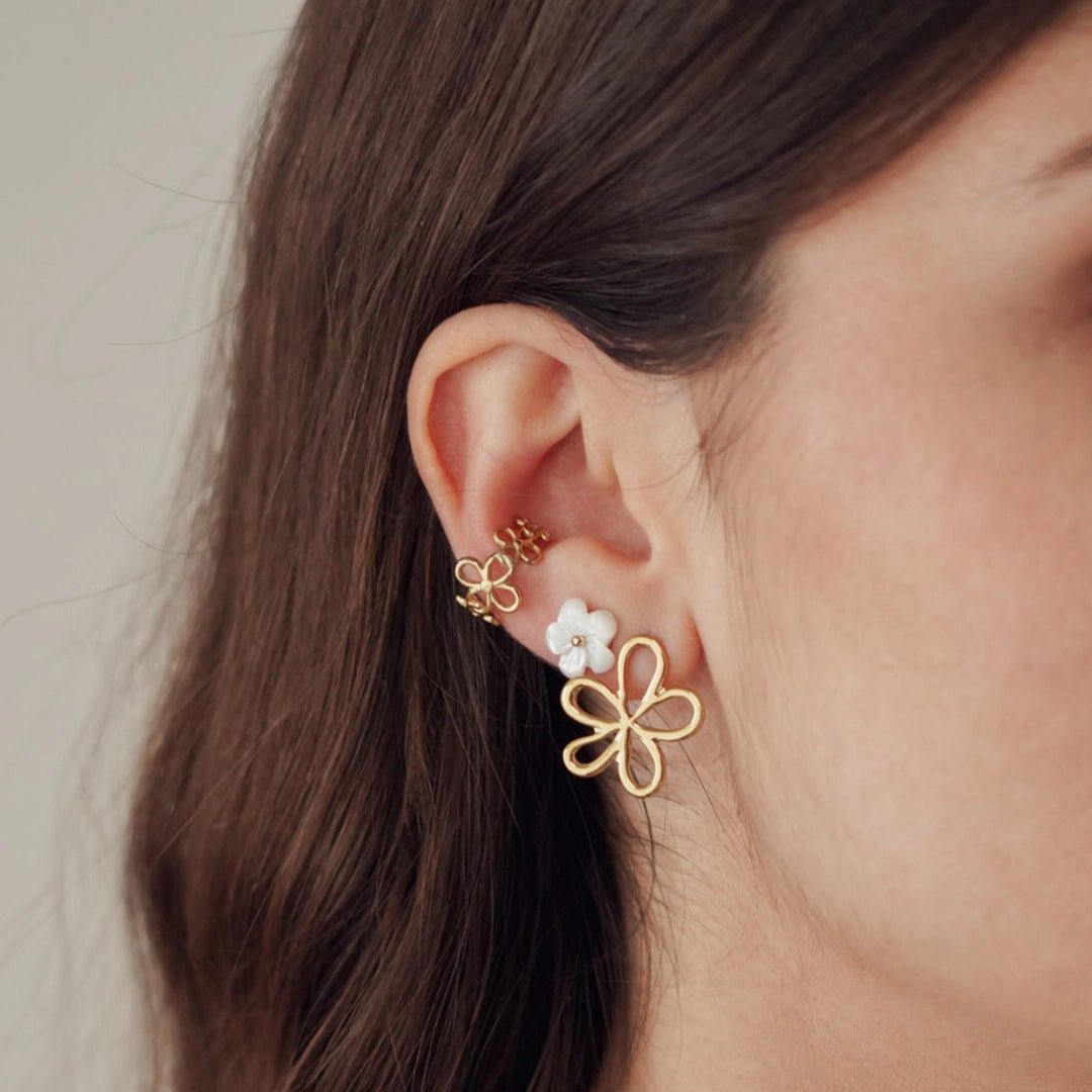 Boucles d'oreilles fleur acien inoxydable doré et blanc avec manchette assortie, portées sur l'oreille d'une femme.