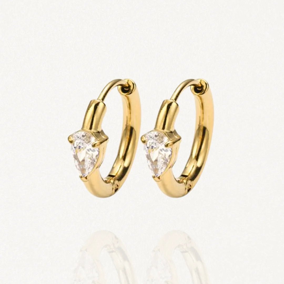 Paire de mini créoles en acier inoxydable doré ornées d'une pierre solitaire forme goutte (poire) sur fond blanc.