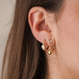 Mini créoles Alison portées en accumulation (stacking) avec d'autres puces d'oreilles dorées sur une composition d'oreille.