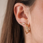 Boucles d'oreilles graphiques Celine forme losange ou hexagone portées au lobe, en accumulation avec le ear climber Ariane.