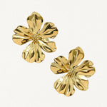 Gros plan boucles d'oreilles motif fleur à pétales ondulés dorés sur fond blanc.