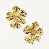 Gros plan boucles d'oreilles motif fleur à pétales ondulés dorés sur fond blanc.