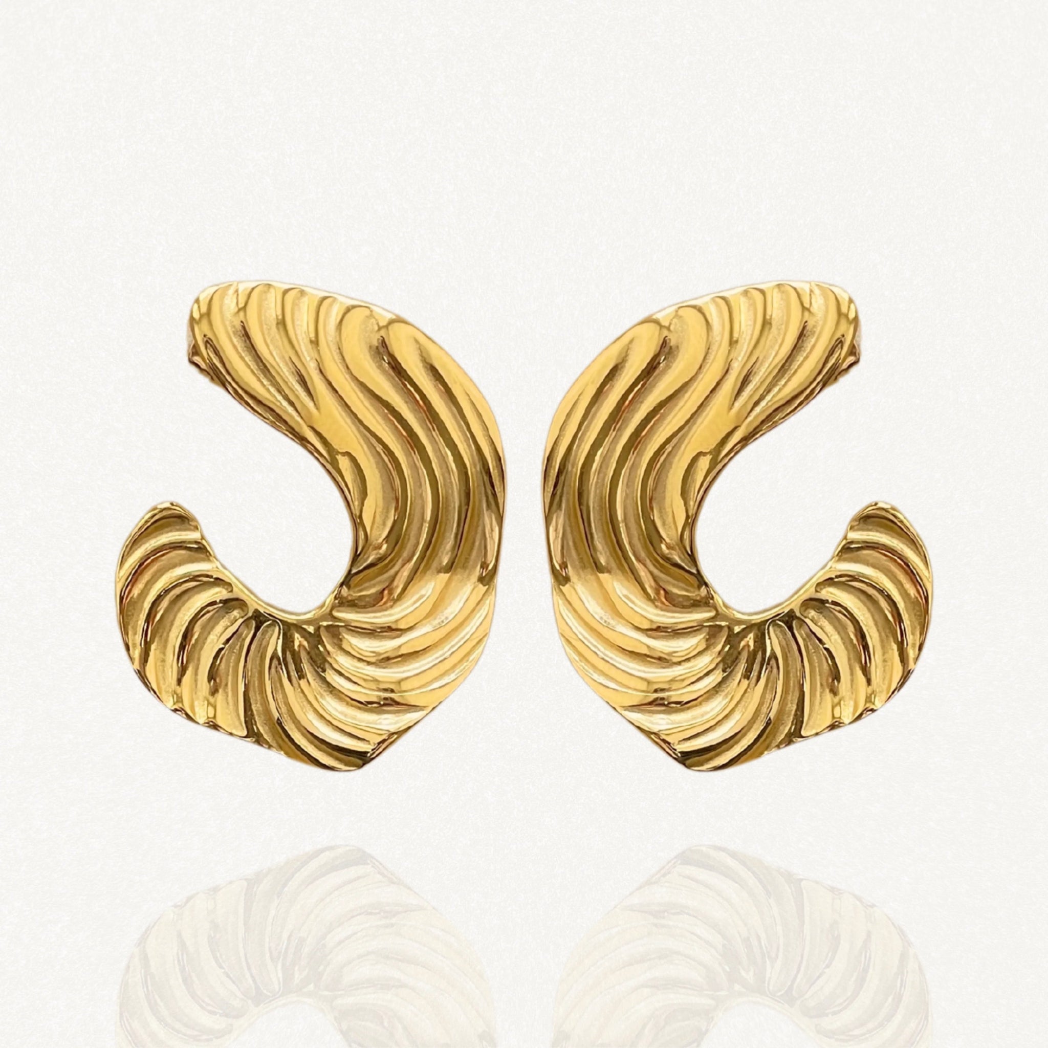 Gros plan boucles d'oreilles créoles ouvertes larges avec relief côtelé ou plissé sur fond blanc.