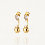 Boucles d'oreilles dessous de lobe (ear jackets) en acier inoxydable doré composées d'une puce strass et d'une goutte dorée pendante.