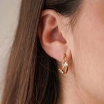 Gros plan boucles d'oreilles Roseline forme C avec pierres scintillantes portées au lobe, style minimaliste.