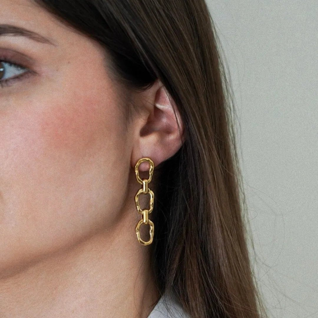 Boucle d'oreille pendante or jaune, 3 maillons ovales martelés irréguliers sur oreille de femme.