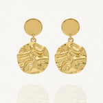 Paire de boucles d'oreilles pendantes en acier inoxydable doré, composées d'un stud rond uni et d'un large pendentif rond martelé irrégulier.