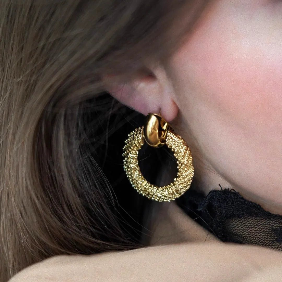 Boucle d'oreille clip-on dorée, anneau à texture granulée sur l'oreille d'une femme; cheveux blonds, dentelle noire.