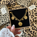 Bracelet à breloques pièces Alice présenté dans son écrin cadeau Maison de l'Amour sur fond léopard.