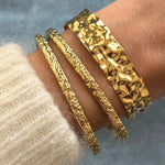 Accumulation de bracelets dorés : le jonc large Anouchka porté avec les joncs fins texturés Azalea.