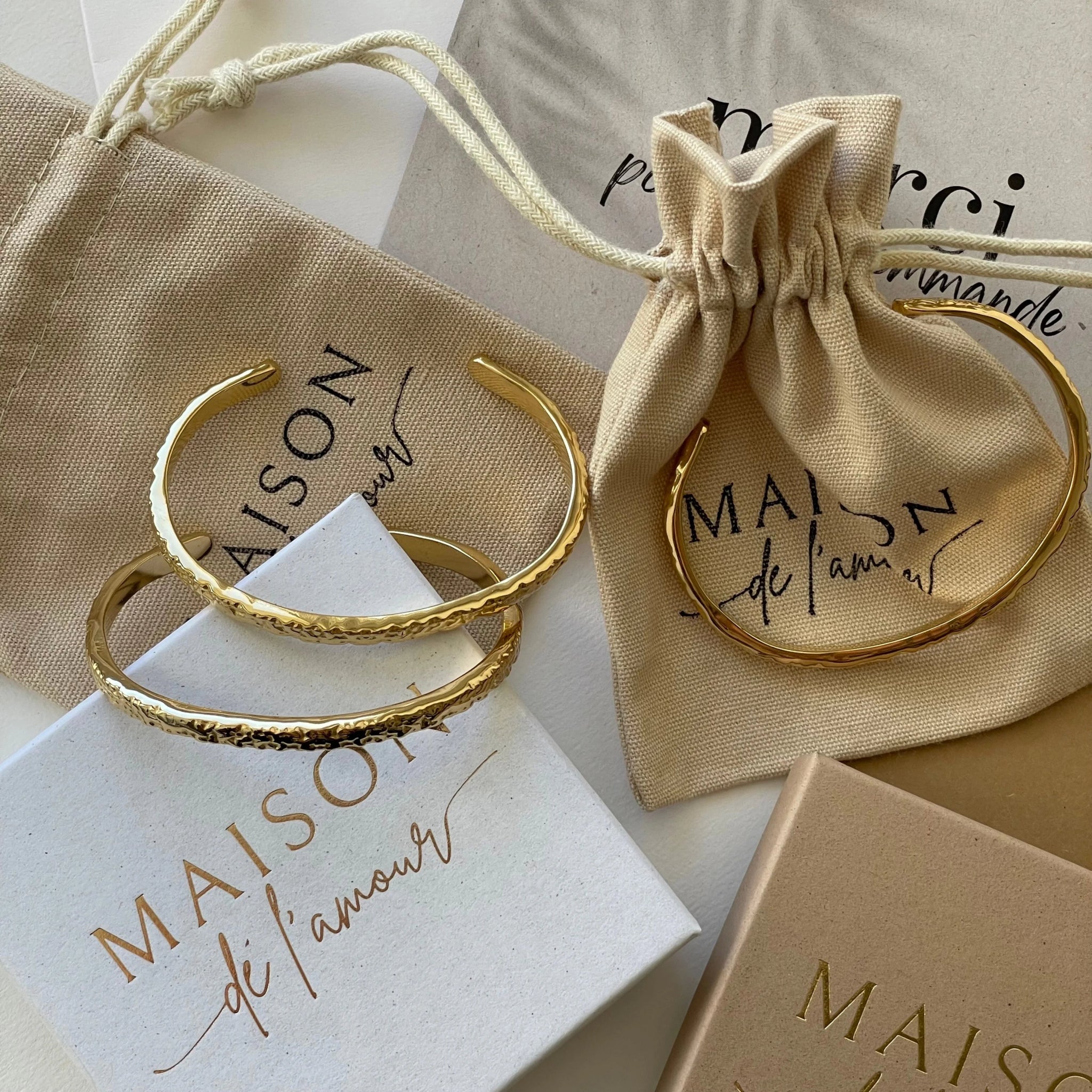 Bracelets joncs Azalea présentés avec leurs pochettes en tissu et boîtes cadeaux Maison de l'Amour.