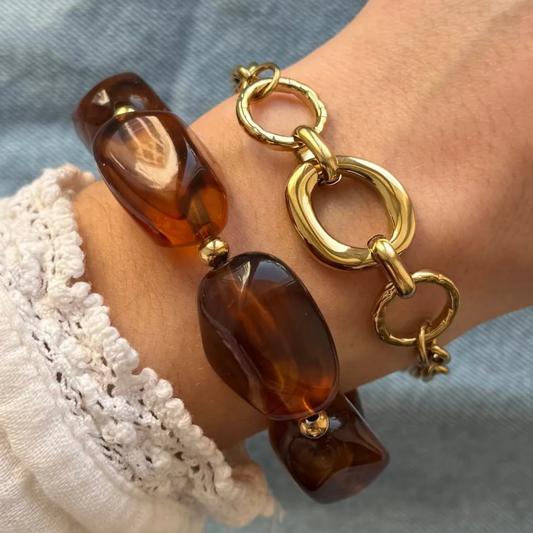Deux bracelets: un à grosses perles marron ambrées et billes dorées, l'autre à maillons dorés (ovales lisses et ronds martelés).