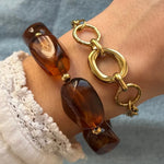 Deux bracelets: un à grosses perles marron ambrées et billes dorées, l'autre à maillons dorés (ovales lisses et ronds martelés).