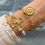 Deux bracelets dorés: l'un avec grande croix martelée, cœur et perles; l'autre chaîne, médaillon d'ange et petite croix texturée.