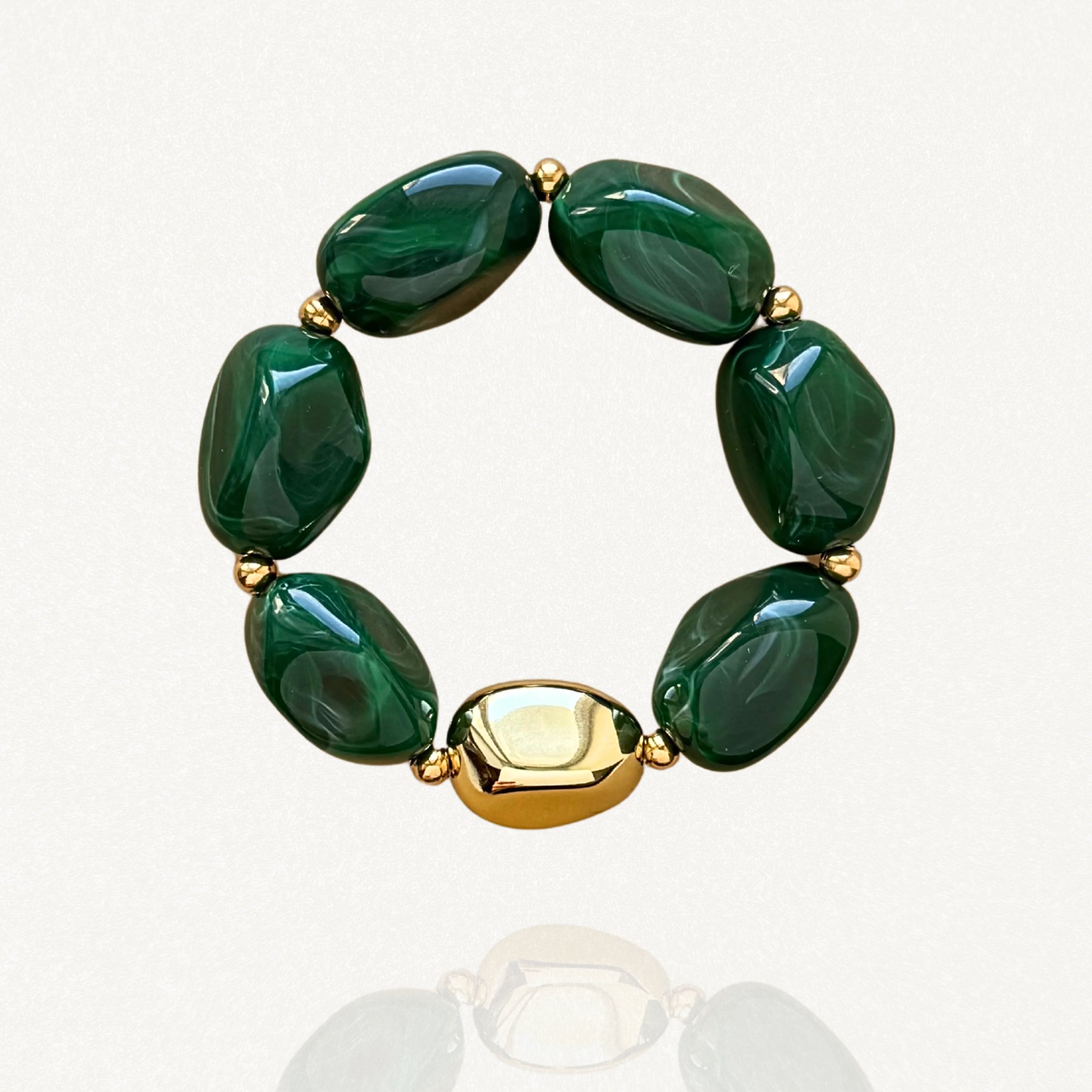 Vue de face sur fond blanc d'un bracelet élastique composé de perles vertes effet pierre et d'une grosse perle dorée lisse.