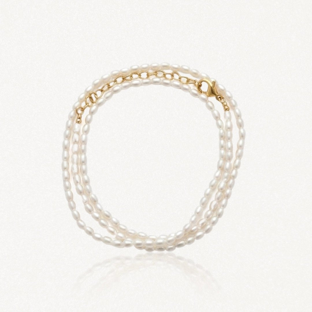 Bracelet multirang en perles d'eau douce ovales blanches avec fermoir et chaîne d'extension en acier inoxydable doré.