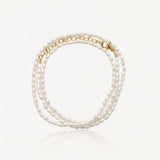 Bracelet multirang en perles d'eau douce ovales blanches avec fermoir et chaîne d'extension en acier inoxydable doré.