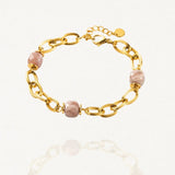 Bracelet grosse maille acier doré avec perles Roses sur fond blanc.