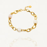 Bracelet grosse maille acier doré avec perles Blanches sur fond blanc.