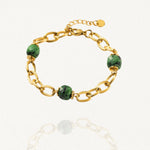 Bracelet grosse maille acier doré avec perles Vertes sur fond blanc.