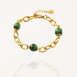 Bracelet grosse maille acier doré avec perles Vertes sur fond blanc.