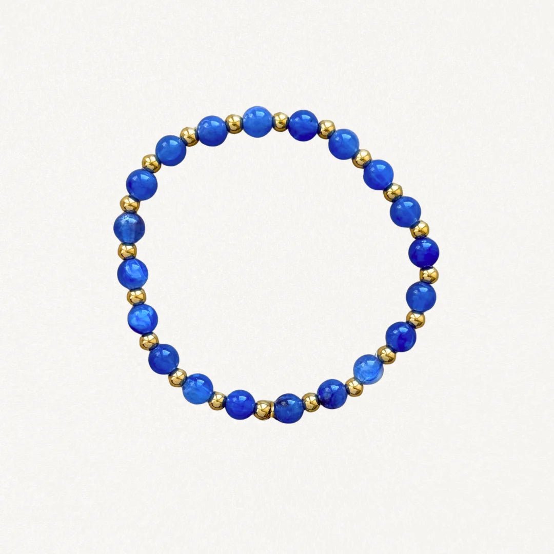 Bracelet fin perles Bleues et billes dorées sur fond blanc.