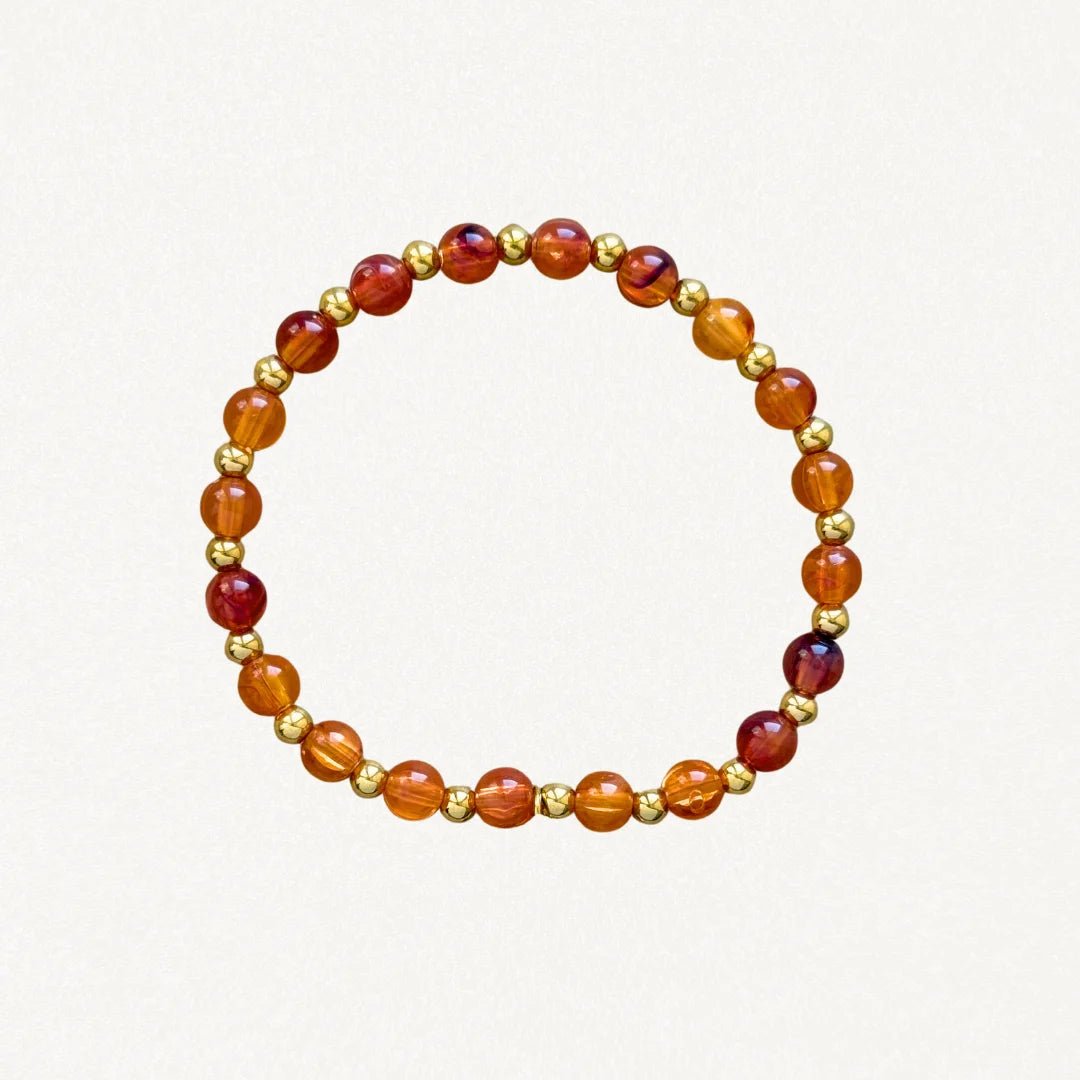 Bracelet fin perles Oranges et billes dorées sur fond blanc.