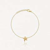 Bracelet fin en acier inoxydable doré, avec une étoile de mer texturée en pendentif et une chaîne réglable.