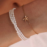 Bracelet chaîne fine en acier inoxydable doré avec pendentif étoile de mer sertie, porté avec un bracelet triple rang de
