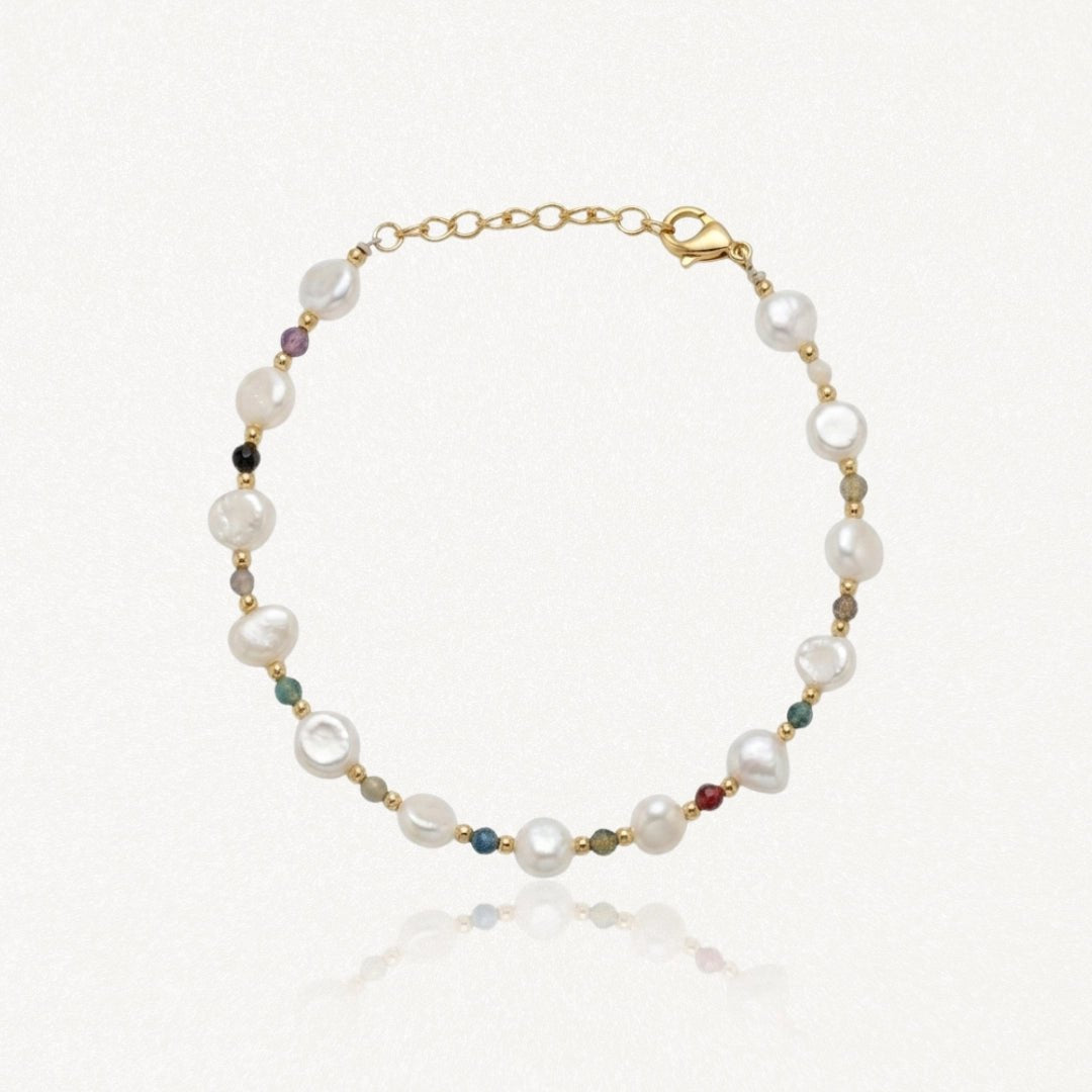 Bracelet en acier inoxydable doré avec perles de culture baroques blanches et petites pierres précieuses colorées.