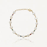 Bracelet en acier inoxydable doré avec perles de culture baroques blanches et petites pierres précieuses colorées.
