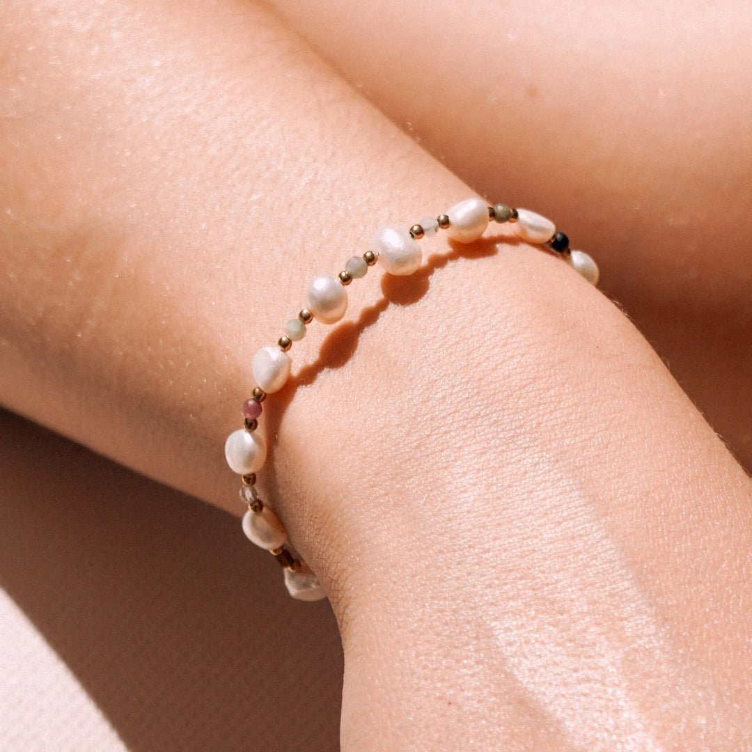 Bracelet en acier inoxydable avec perles de culture baroques, perles dorées et pierres naturelles colorées au poignet.