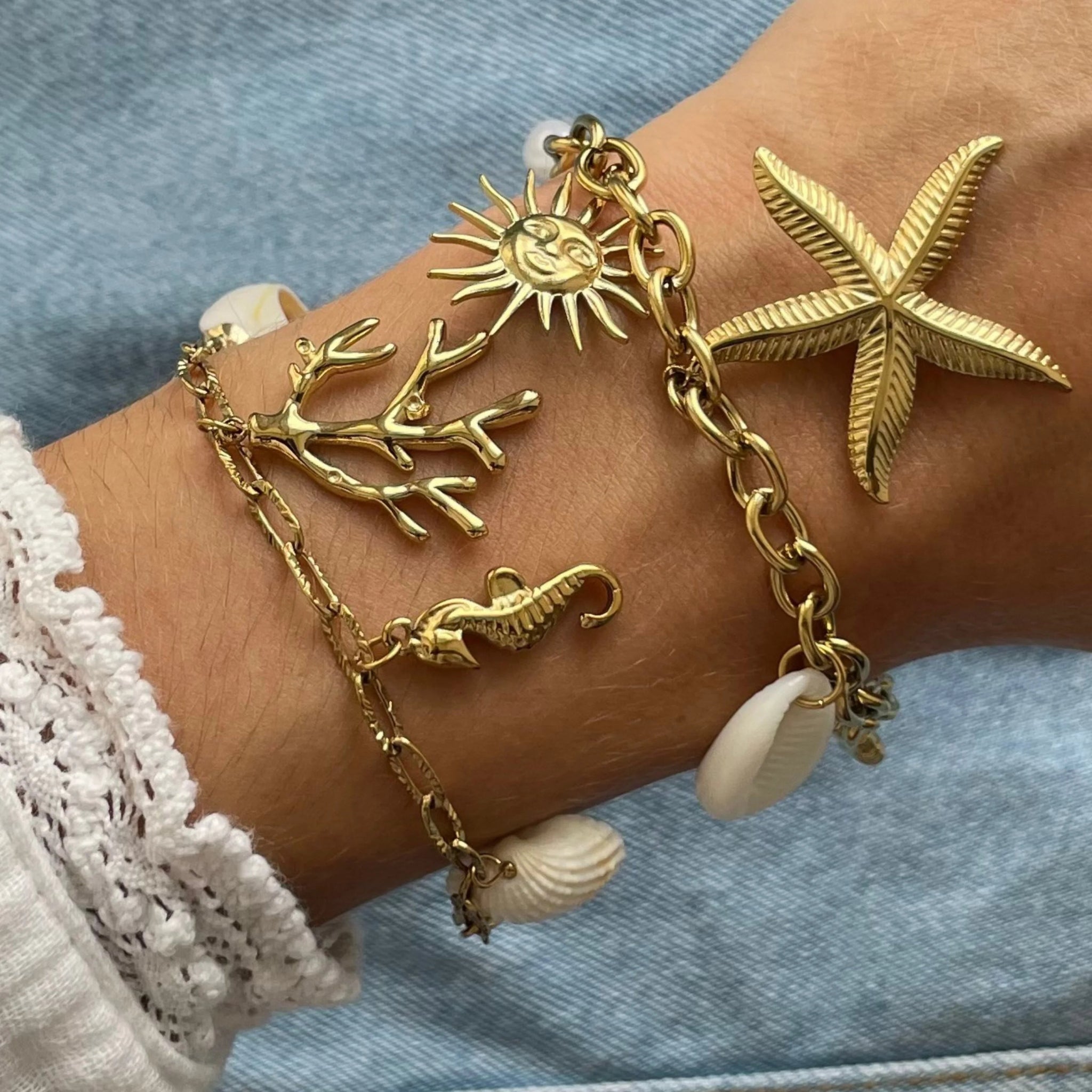 Bracelet à charms marins Maeva porté en accumulation (stacking) avec un autre bracelet coquillage pour un look de sirène estival.