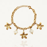 Vue d'ensemble bracelet chaîne doré avec multiples pendentifs fleurs dorées et fleurs en perles sur fond blanc.