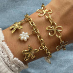 Bracelet à breloques fleurs Marga porté en accumulation (stacking) avec un autre bracelet chaîne à motifs floraux ajourés.