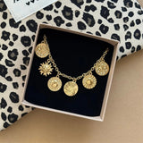 Bracelet à charms médailles Mariana présenté dans son écrin cadeau Maison de l'Amour sur fond léopard.