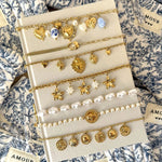 Présentation de la collection de bracelets dorés à charms (soleils, étoiles, pièces) incluant le modèle Mariana.