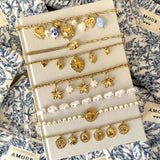 Présentation de la collection de bracelets dorés à charms (soleils, étoiles, pièces) incluant le modèle Mariana.