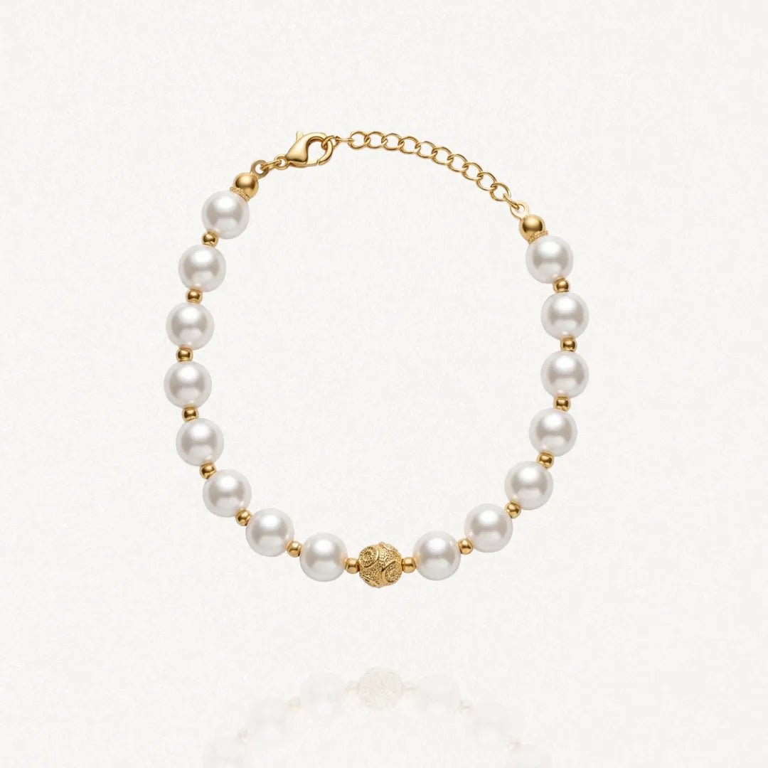 Bracelet MARYLINE composé de perles rondes blanches alternant avec de petites perles dorées, et une perle centrale dorée ornée. Fermoir mousqueton doré.