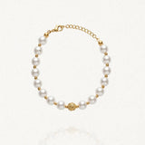 Bracelet MARYLINE composé de perles rondes blanches alternant avec de petites perles dorées, et une perle centrale dorée ornée. Fermoir mousqueton doré.