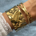 Bracelet jonc croisé Nyla porté en accumulation (stacking) avec la manchette large Sofia pour un jeu de volumes.