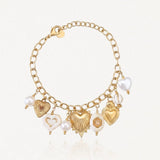 Bracelet en acier inoxydable doré avec multiples breloques cœurs (texturés, nacrés) et perles, dont une en forme de cœur.