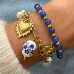 Bracelet à breloques Paulette porté en accumulation avec un bracelet perles bleues assorti.