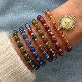 Accumulation de bracelets colorés à breloque cœur sacré (rouge, vert, bleu, orange) portés ensemble